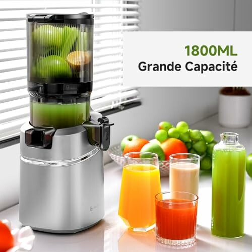 Extracteur de jus avec fruits et verres de jus de différentes couleurs.